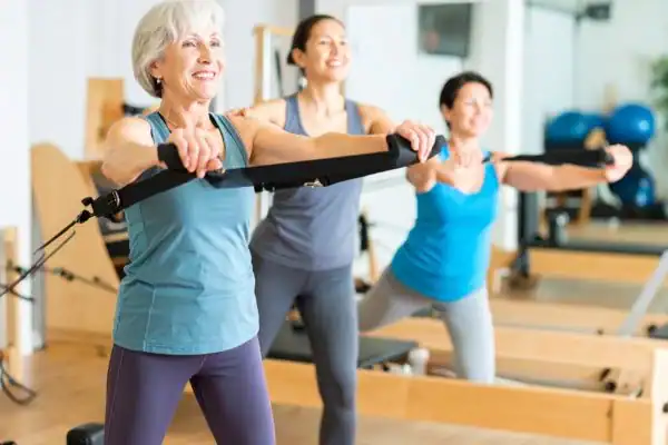 Toning Arms After 60: Empowering Womens Fitness Through Effective Weight Training 2 older woman doing weight training Falkirk and resistance in the gym to tone upper arms